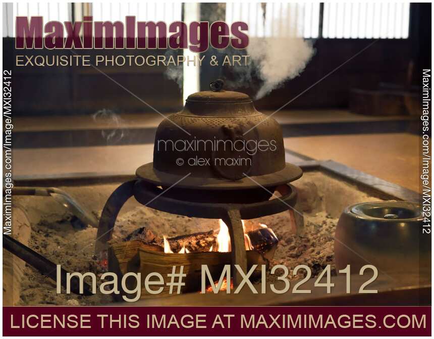 Japanese cast iron kettle steaming on fire in a sunken hearth Irori Shirakawa-go village Japan