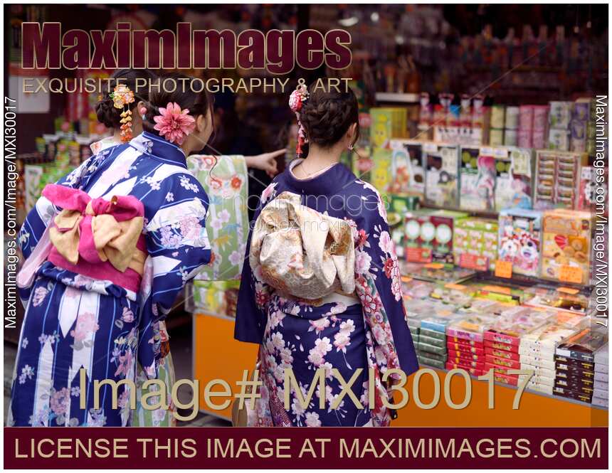 Japanese girls in bright Yukatas stopped by a shop with traditional local Kyoto treats