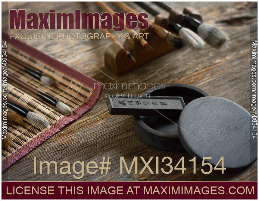 Japanese sumi-e painting art tools brushes ink stone and black ink stick on rustic wooden table