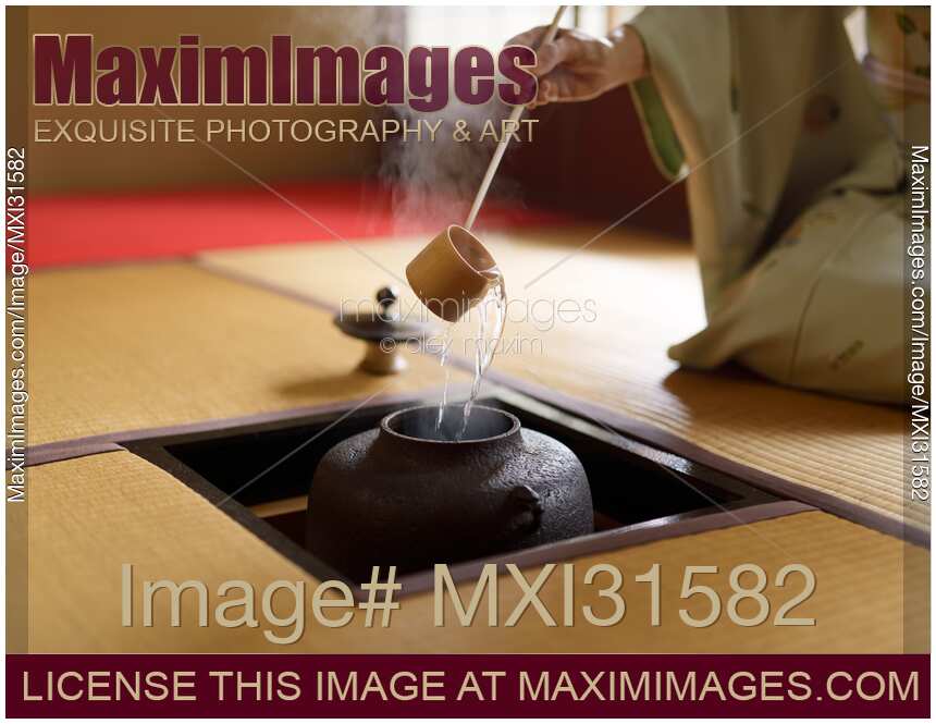 Japanese woman tea ceremony master pouring hot water from a pot with a ladle in a traditional teahouse