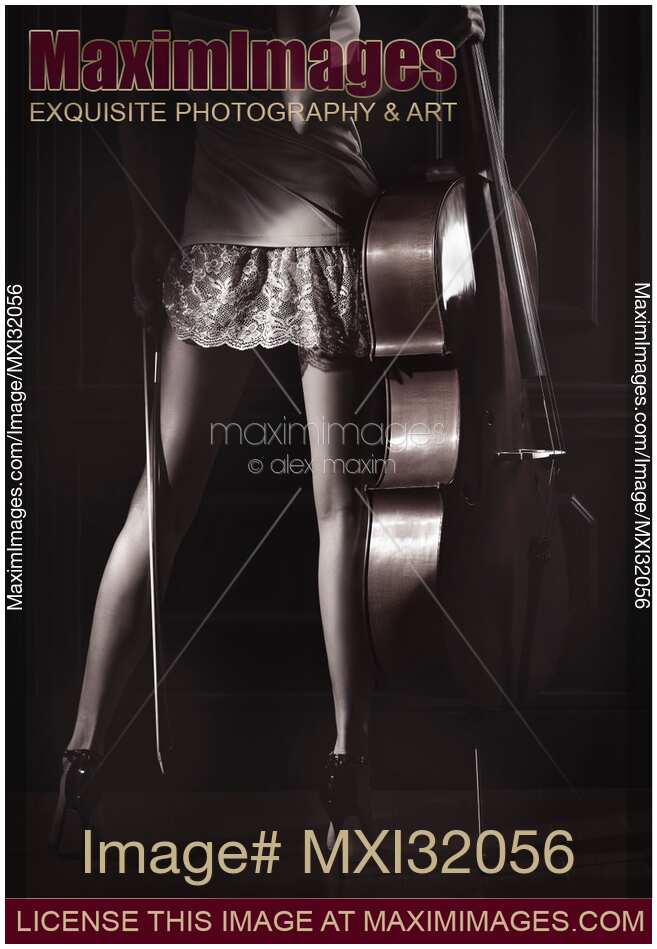 Legs of a sexy young woman in a night gown holding a cello in a dark room with dramatic light