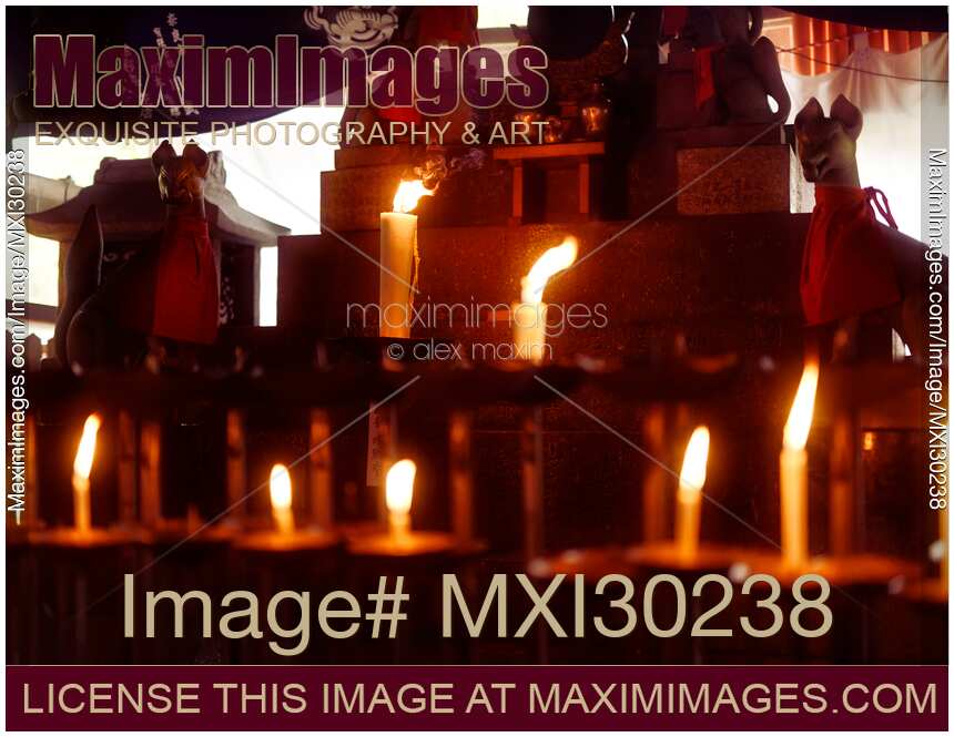 Lit candles at a small Shinto shrine with Kitsune foxes at Fushimi Inari in Kyoto