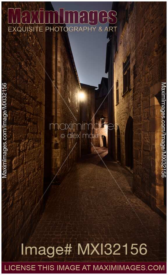 Long narrow old cobbled street with French stone houses in twilight