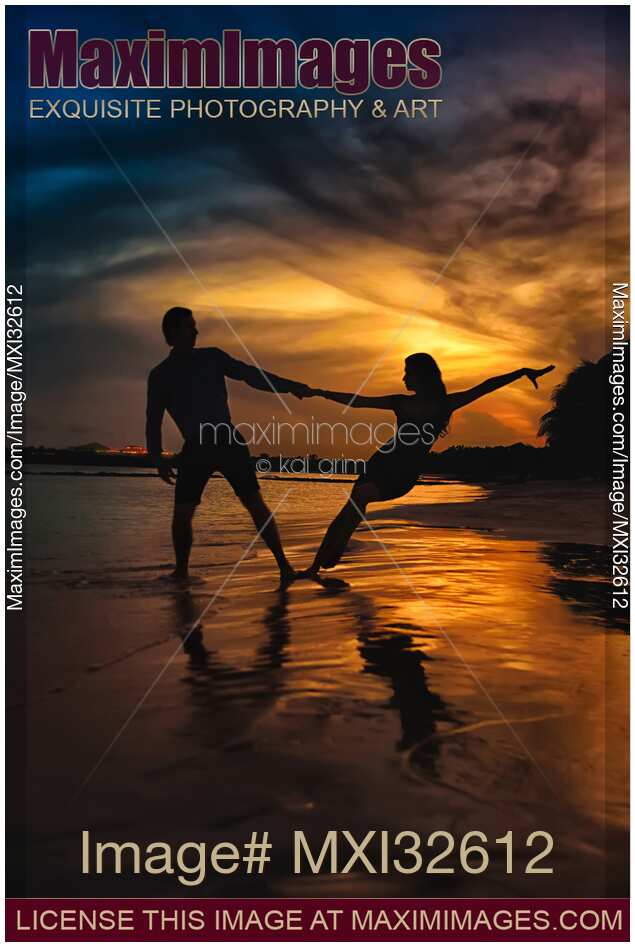 Man and woman dancing at a seashore in dramatic sunset Couple holding hands dark silhouette against sunset sky