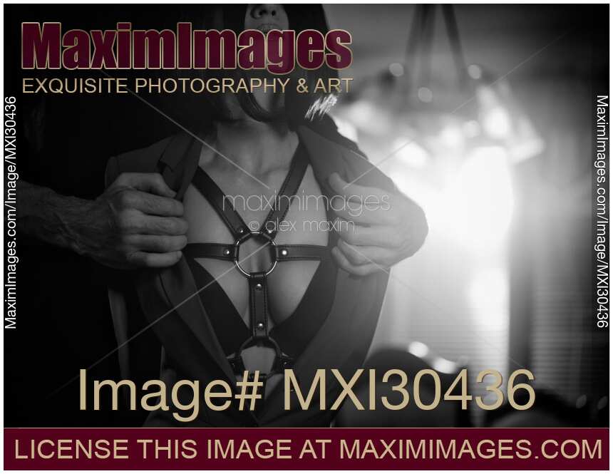 Man hands taking off woman clothes revealing leather bondage on her chest Black and white sexy couple portrait