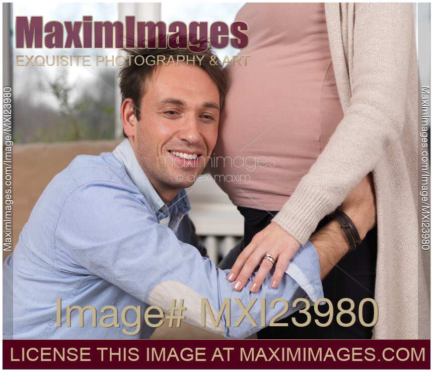 Man listening to baby moving inside woman's belly