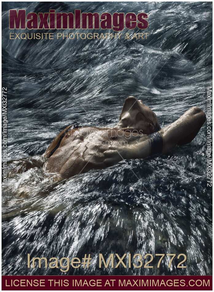 Man with naked wet body lying in rushing turbulent water of a river Dramatic moody photograph
