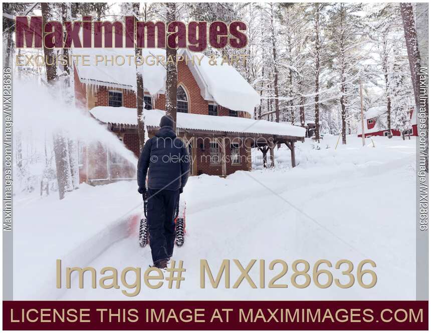 Man with snow blower clearing driveway in Canadian winter