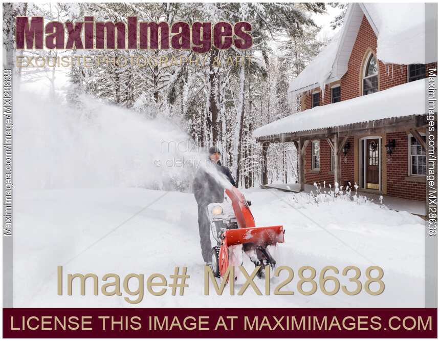 Man with snowblower clearing driveway from snow