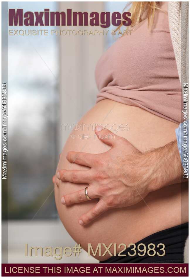 Man's hands on pregnant woman's belly