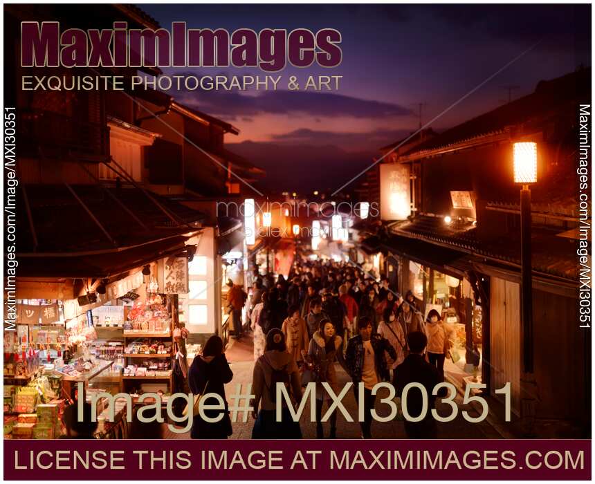 Matsubara dori street in Kyoto at night with brightly lit souvenir shops and street lights busy with tourists
