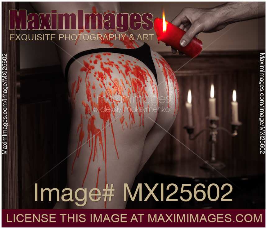 Melted red wax dripping from candle on sexy woman body