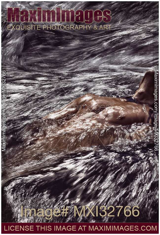 Muscular man half-naked body submerged in rushing river water or stormy sea waves Dramatic fine art portrait