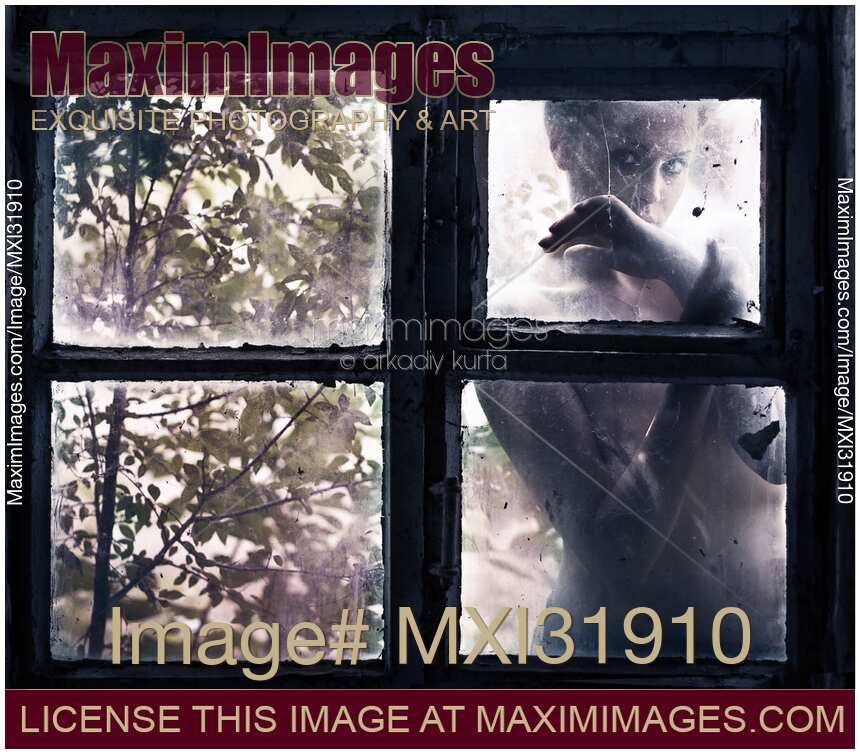 Mysterious portrait of a woman behind a closed dusty window pane of an old house