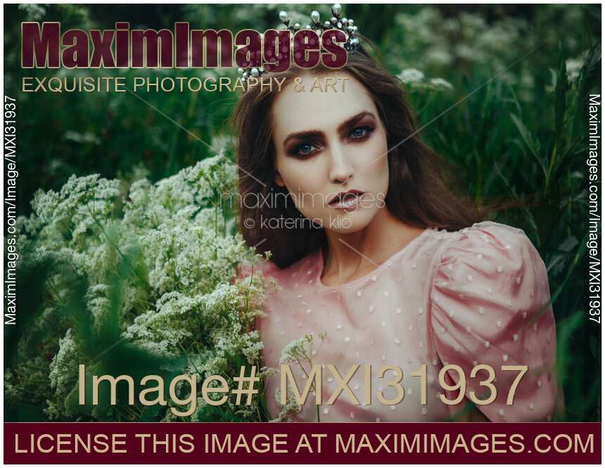 Mythical beauty portrait of a woman in a princess crown in a field of wild yarrow