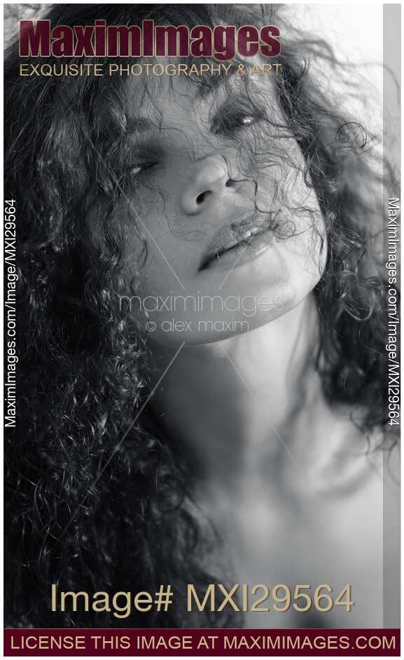 Natural beauty portrait of curly long hair covering young woman face Black and white