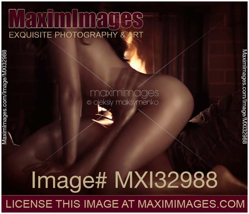 Nude couple with sweaty bodies making love by a fireplace