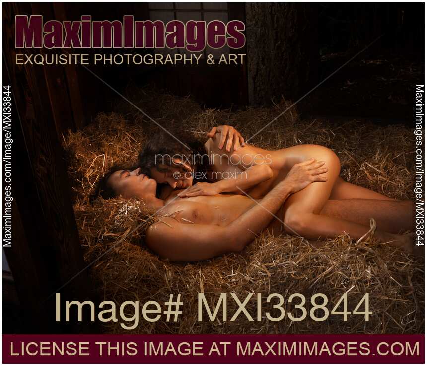 Nude sexy couple man and woman lying relaxed naked on straw in embrace in warm golden light