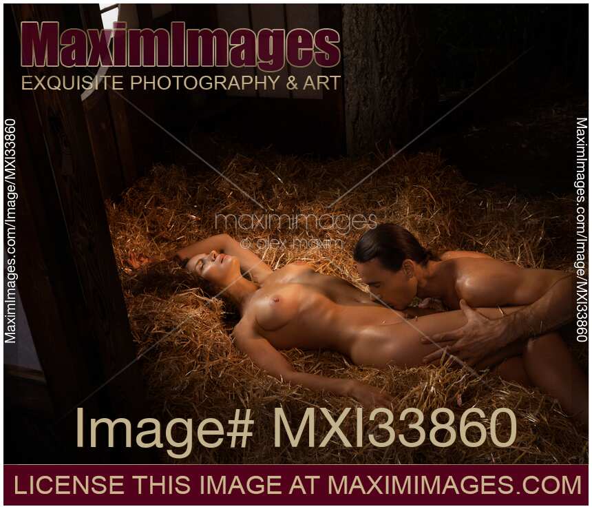 Nude sexy couple man and woman making love on straw in dim warm golden light. Sensual romantic scene.