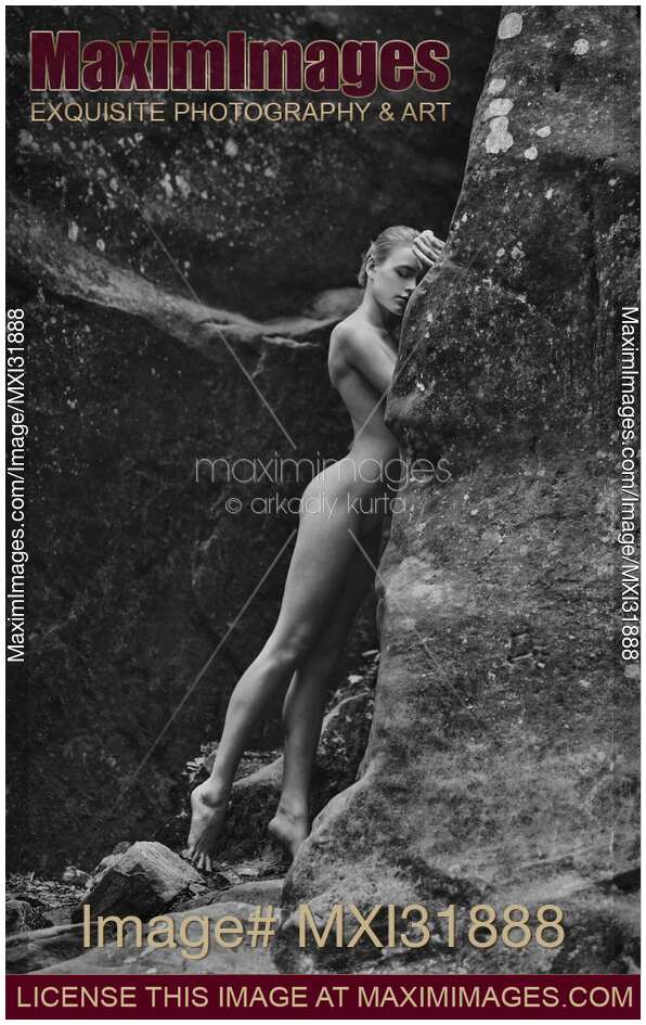 Nude woman gracefully leaning against rocks in the nature tranquil art nude portrait