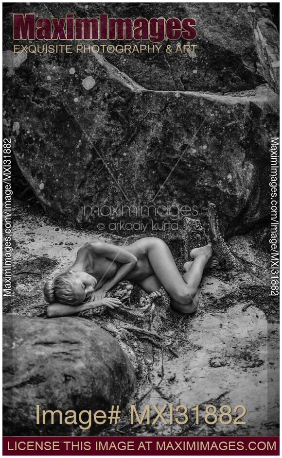 Nude woman lying down curled up on the ground in a forest