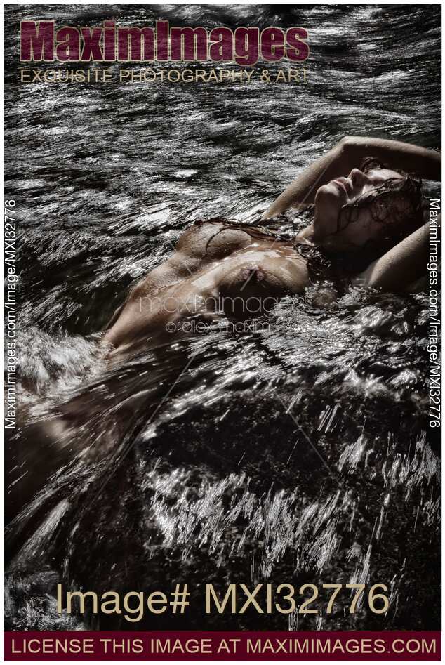 Nude woman lying in wild water of a rushing river her bare breasts and wet body arched above water