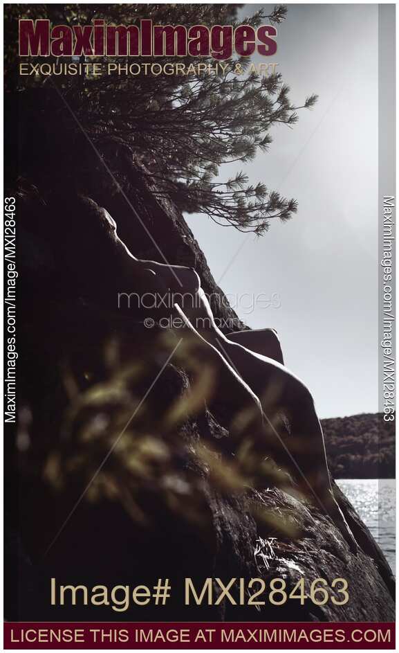 Nude woman lying on rocks in sunshine