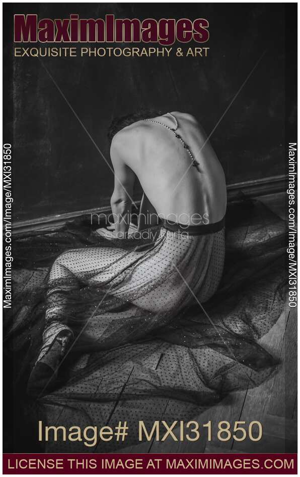 Nude woman sitting curled on the floor with an Ankh cross on her back