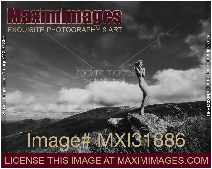 Nude woman standing gracefully on rocks in mountain landscape scenery Black and white