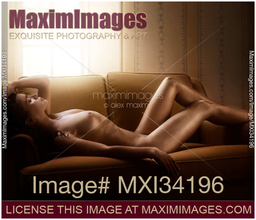 Nude young woman with sexy shiny golden skin and gorgeous naked body lying on a couch in a sensual pose