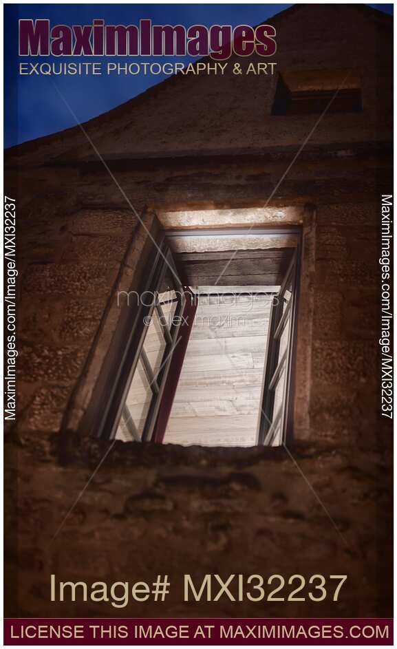 Open window of an old stone house illuminated from inside at night artistic concept