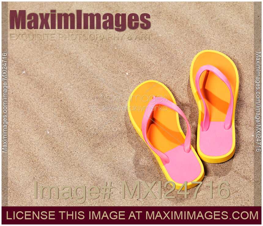 Orange flip flops on beach sand