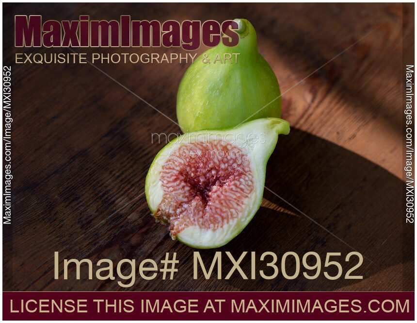 Organic fresh ripe figs on a table one fruit sliced in half showing purple pulp