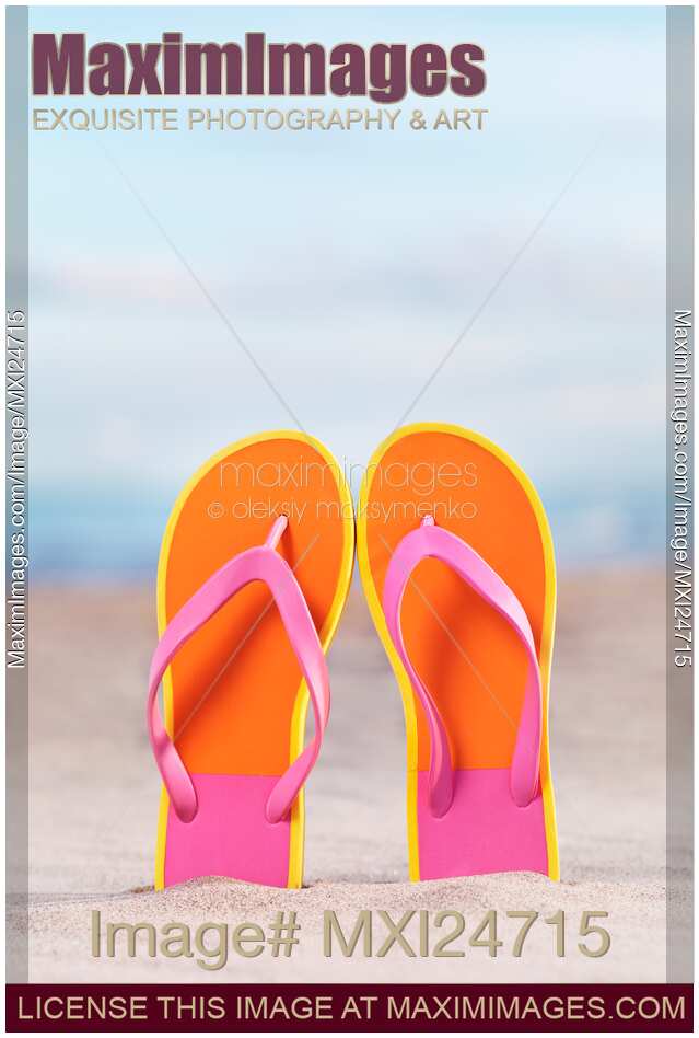 Pair of bright orange flip flops at the beach