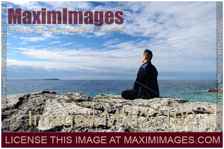 Person meditating on a shore of a lake