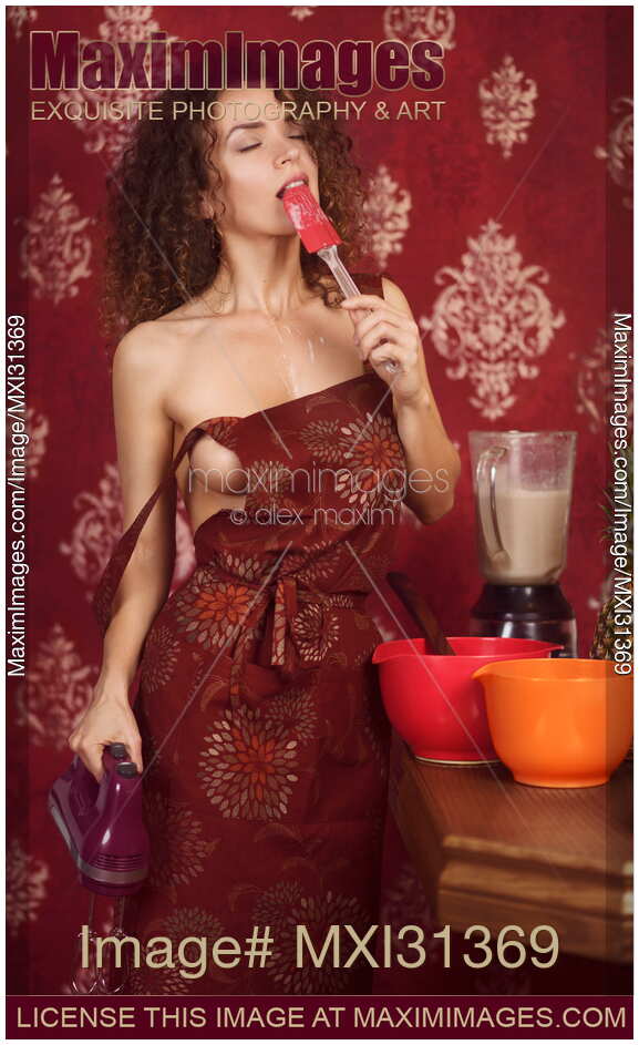 Playful sensual portrait a sexy woman housewife cooking in the kitchen tasting food dripping from a spatula on her naked chest