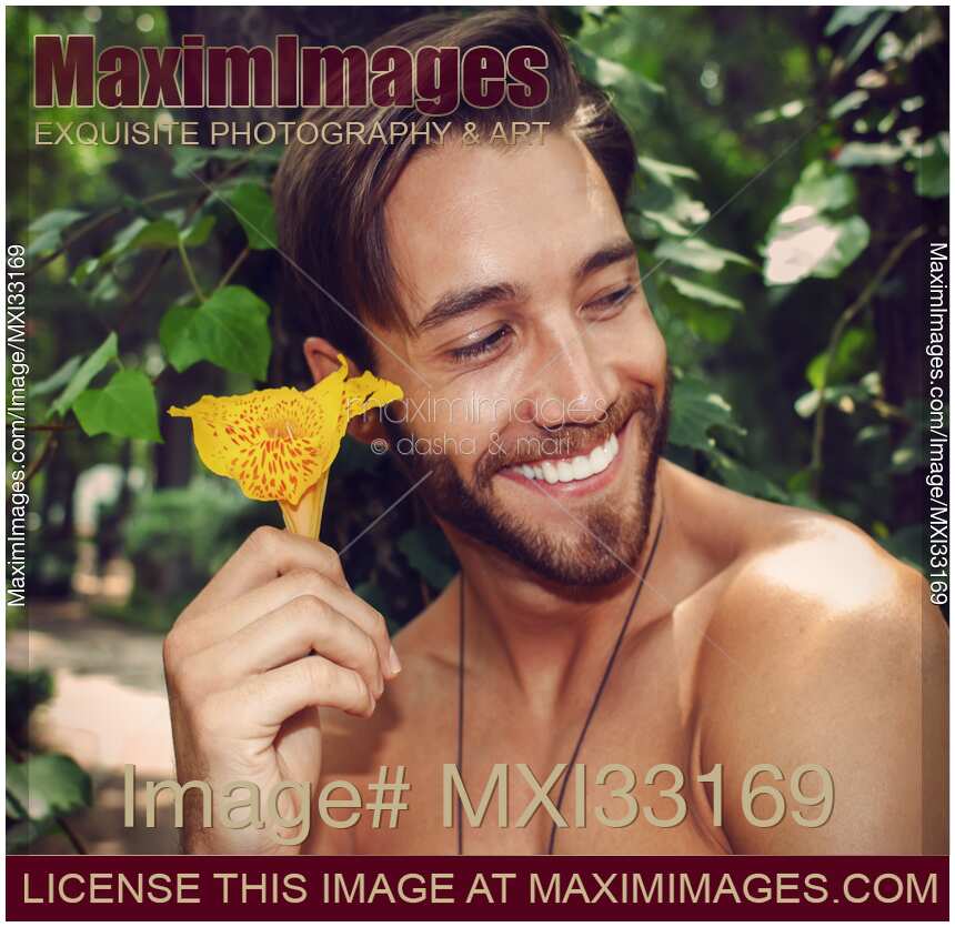 Portrait of a handsome young man holding a flower with a short bear and mustache on his smiling face