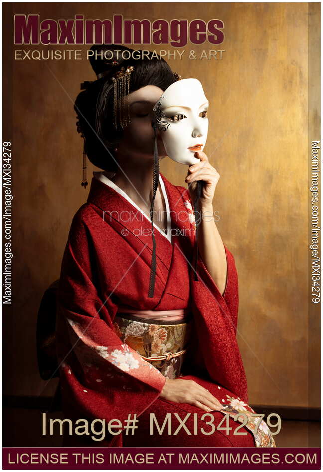 Portrait of beautiful geisha holding white theatrical mask in her hand in front of her face