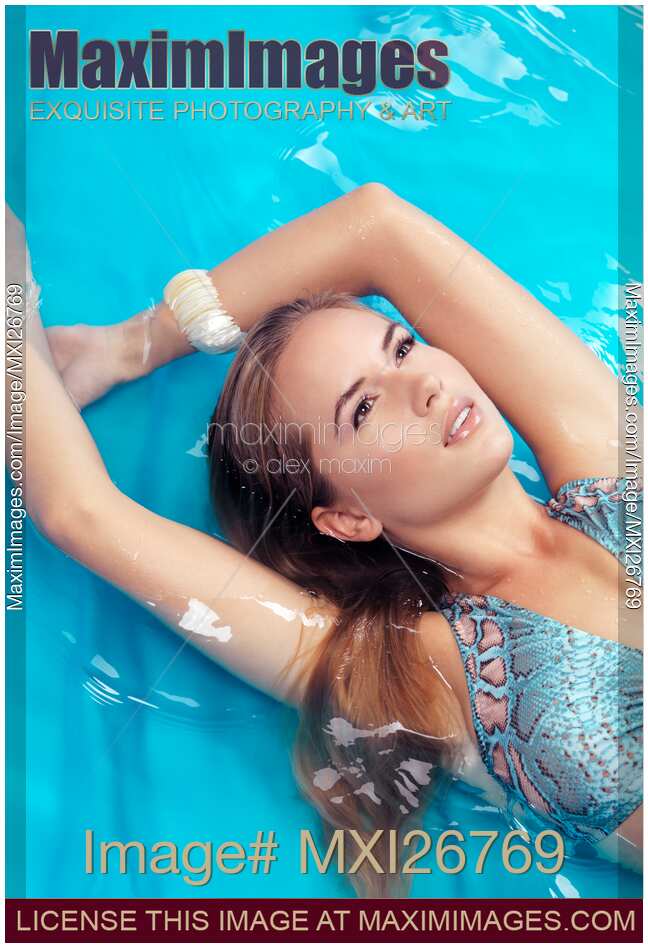 Portrait of beautiful woman lying in blue water