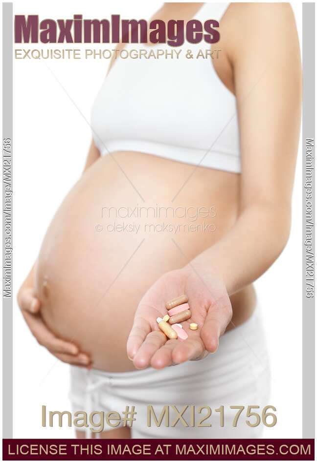 Pregnant Young Woman Holding Pills in Her Hand
