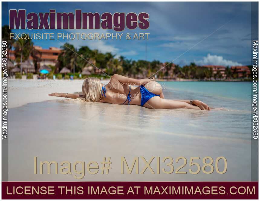 Rear view of a sexy woman in bikini swimsuit lying on a sandy shore of Caribbean Sea in Cancun