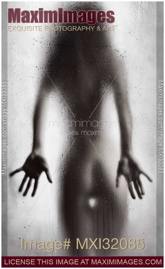 Rear view of nude sexy woman in a provocative pose standing behind wet shower glass Black and white