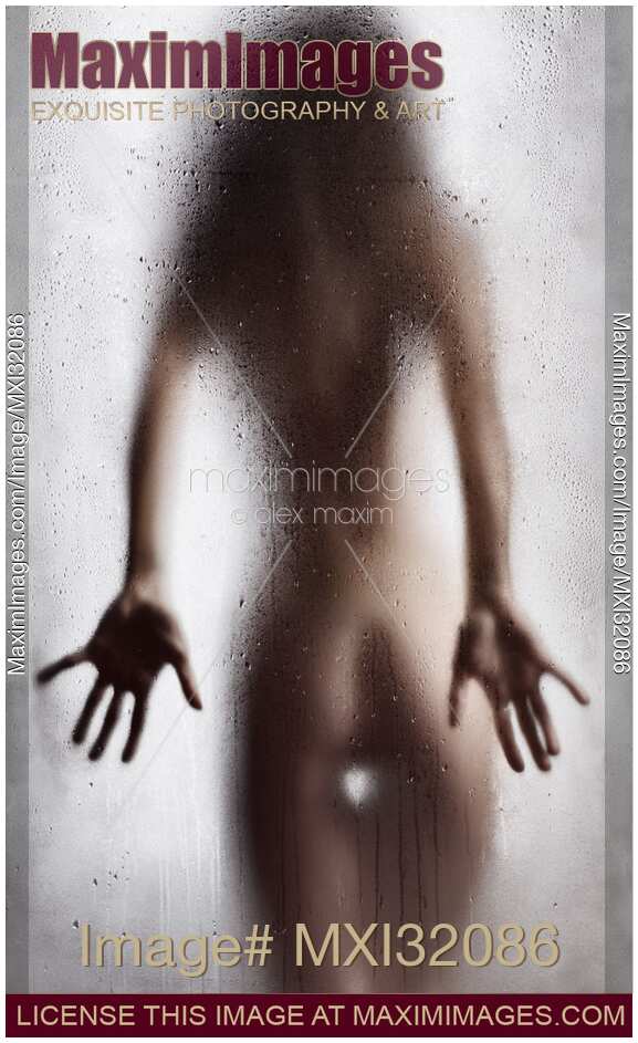 Rear view of nude sexy woman in a provocative pose standing behind wet shower glass
