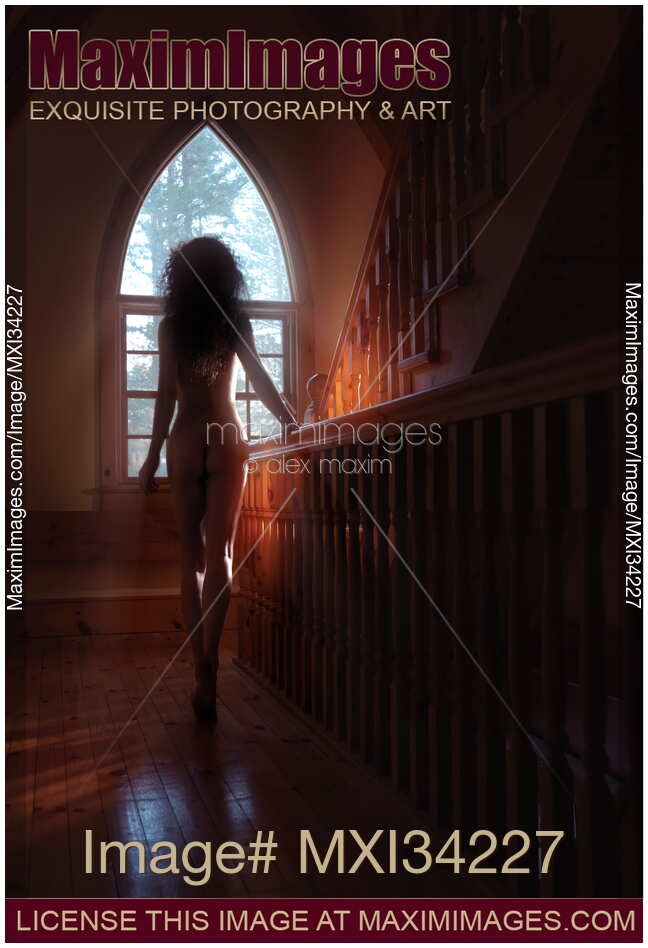 Rear view silhouette of beautiful naked woman walking to a staircase window in dim sunlight