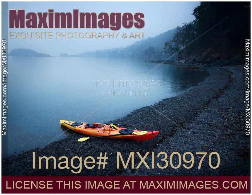 Red kayak on a sea shore in yearly morning mist