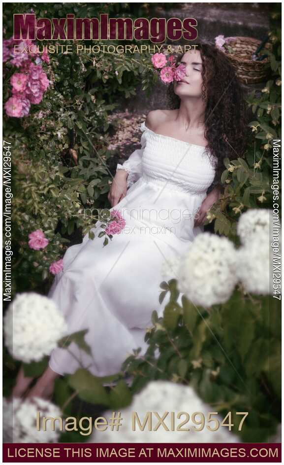 Romantic portrait of a woman smelling roses lying on stairs in a garden