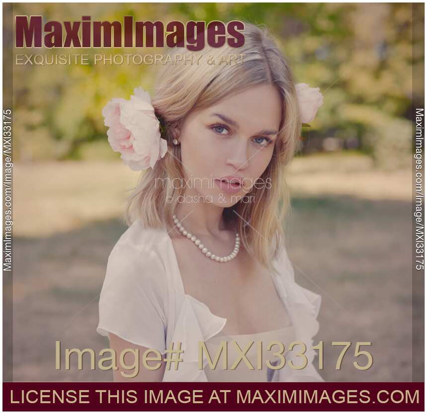 Romantic portrait of a young pretty woman with a pink flower in her blond hair