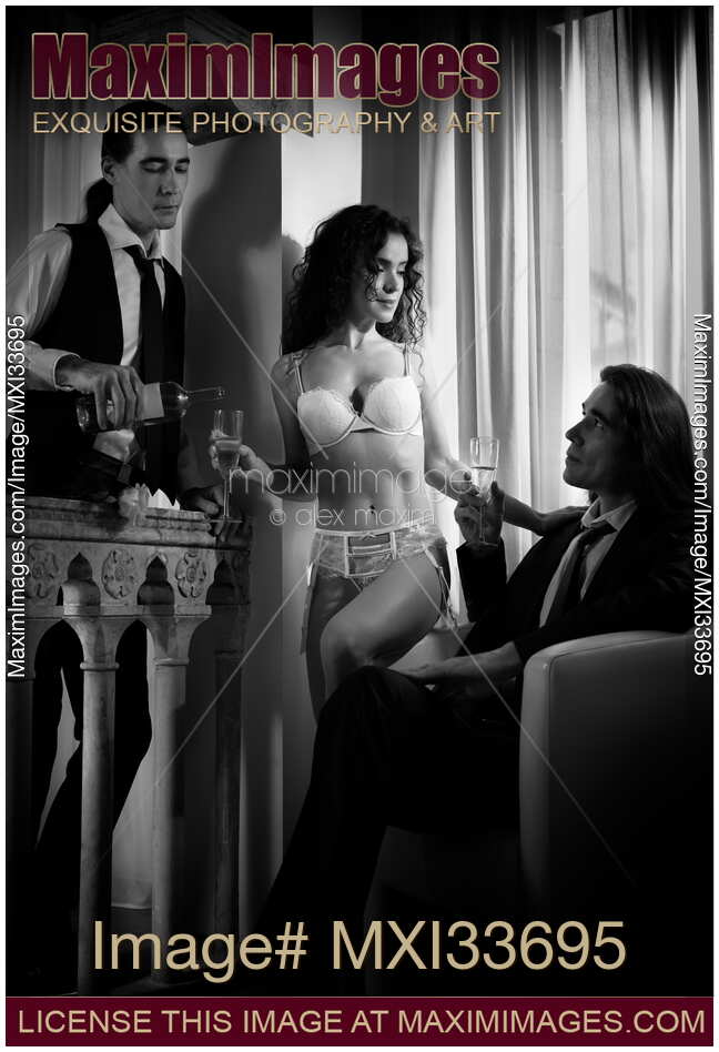 Romantic trio, implied sensual black and white photograph of sexy lady in lingerie drinking wine with two gentlemen