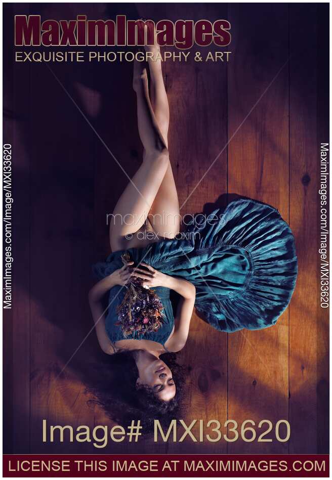 Sensual art nude portrait of woman in green dress with bare legs lying half naked on the floor with flowers