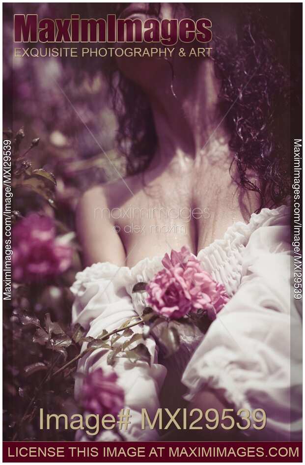 Sensual artistic closeup portrait of beautiful woman with pink roses in wet dress under a rain